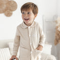 Afbeelding laden in Galerijviewer, Beige pyjama Lou met wit biesje – zacht en stijlvol babypakje, perfect om te laten personaliseren.