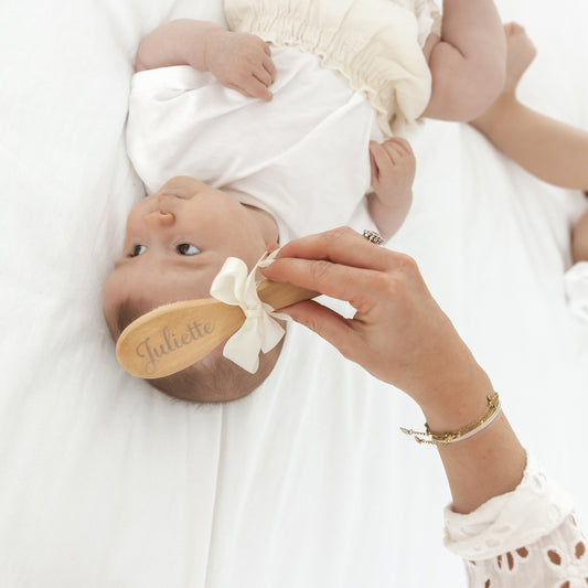 Detail van houten baby haarborstel met gegraveerde naam – natuurlijke houtstructuur en zachte borstelharen