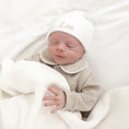 Afbeelding laden in Galerijviewer, Detail van babymutsje – fijn geborduurde naam in zachte tint, subtiele afwerking en rekbare stof voor newborn baby’s
