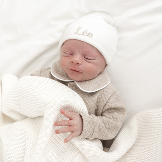 Detail van babymutsje – fijn geborduurde naam in zachte tint, subtiele afwerking en rekbare stof voor newborn baby’s