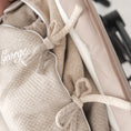 Afbeelding laden in Galerijviewer, Detail van beige voetenzak voor kinderwagen – strikjes aan de zijkant en fijne bies voor elegante afwerking

