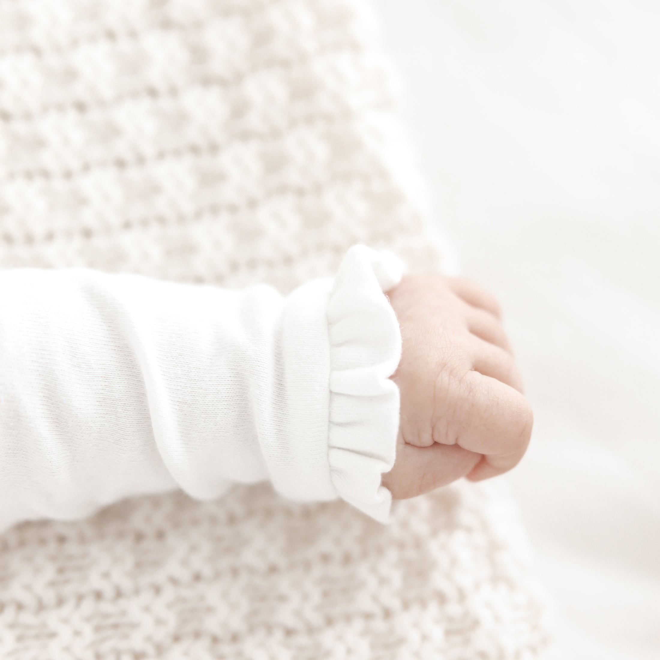 Ruffeltjes aan de mouwtjes van Kruippakje Alix – subtiele, verfijnde afwerking van zacht babykruippakje met naam